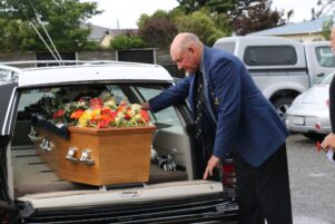 Former Featherston rugby player and Wairarapa-Bush representative Neville Taylor lays a flower on Ron's coffin. PHOTO/HAYLEY GASTMEIER