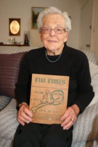 Dorothy Daysh showing the ‘Tiki Times’, a booklet of the camp newspaper for prisoners of war at Milwitz, Upper Silesia, from between July 1944 and January 1945. The camp, E535 was a working camp attached to Stalag VIIIB, Teschen.